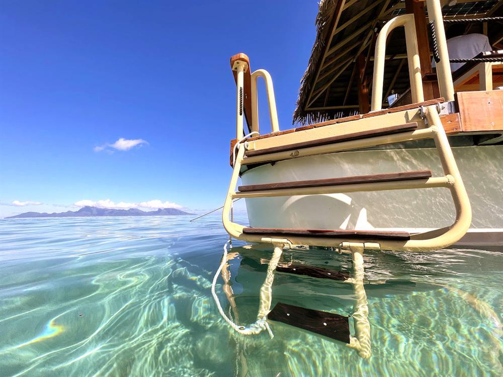 L'échelle de bain plonge dans l'eau cristalline, Moorea au loin