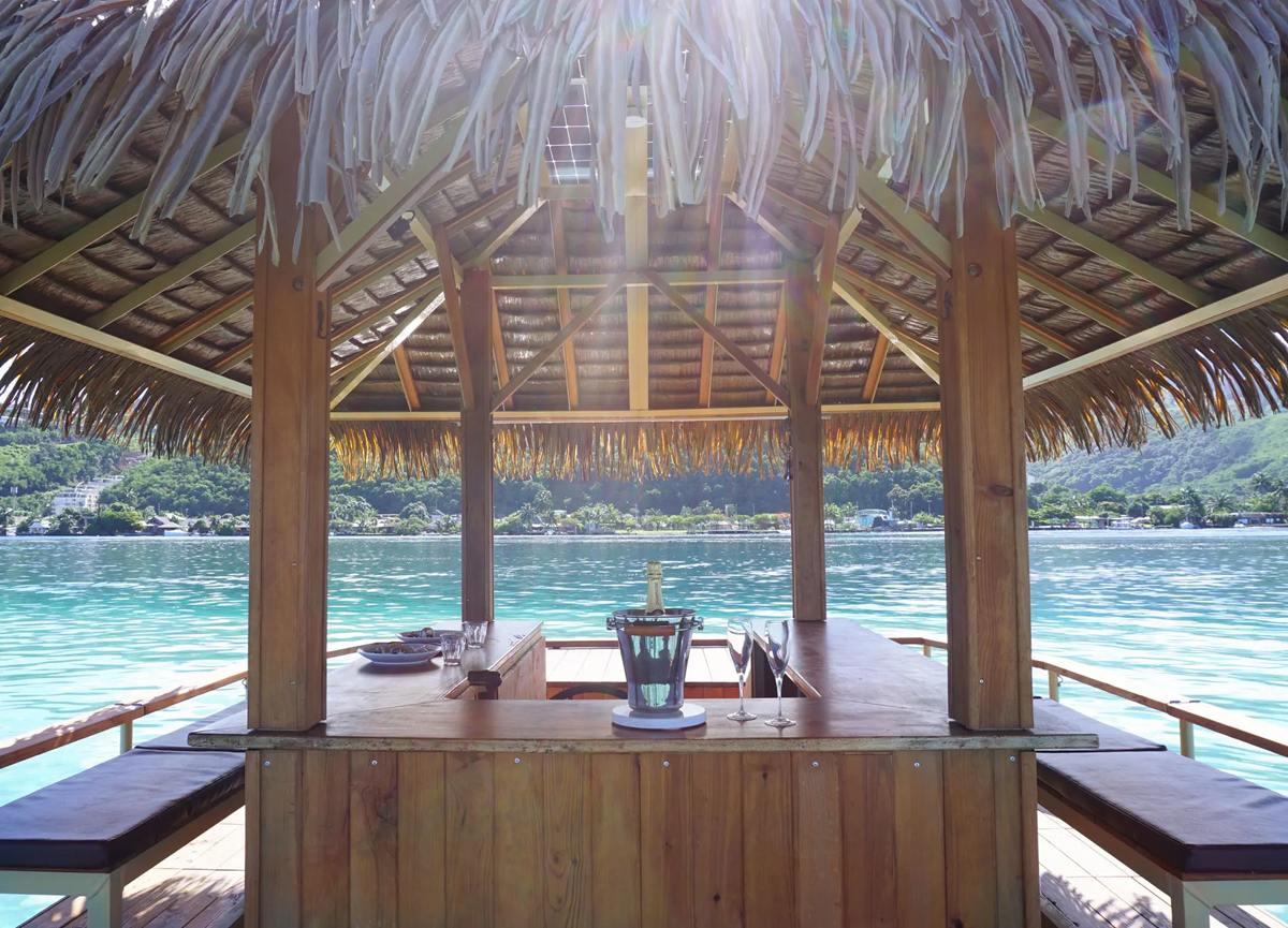 Sous la paillote : bar en bois, banquettes et vue sur la côte de Tahiti
